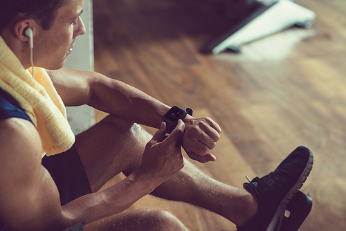 Confident young athlete monitoring fitness progress after completion of intensive training at modern gym