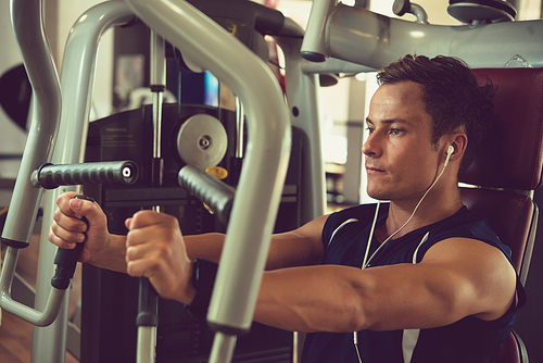 Handsome healthy man working out on simulator