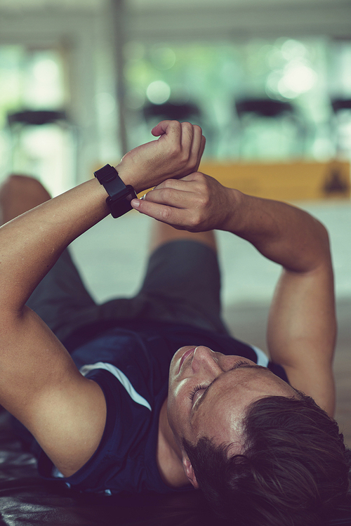 Exhausted young sportsman checking health app on smart watch