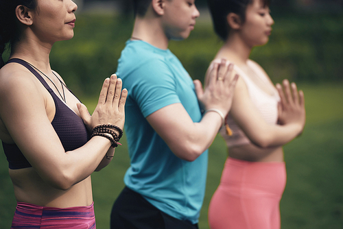 Cropped image of young people meditating together outdoors, selective focus