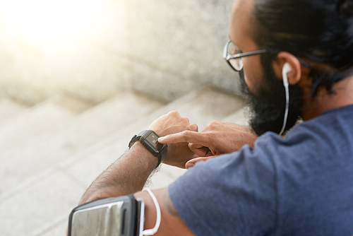 Active man checking heart rate on screen of his smartwatch