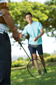 Teenage boy playing bambinton with his dad in city park