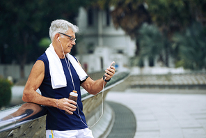 Healthy senior man checking smartphone after training outdoors