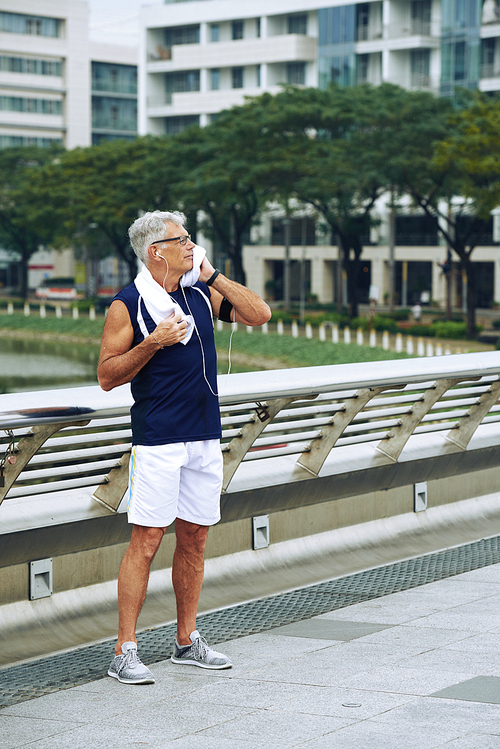 Senior man wiping sweat after jogging in the morning