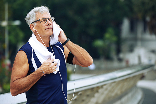 Portrait of elderly sportsman wiping sweat after jogging