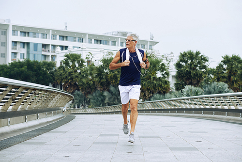 Active senior man running in the street