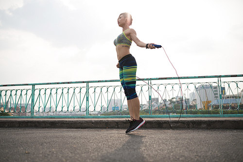 Slim young Asian woman exercising with skipping rope