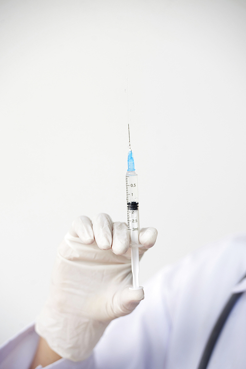 Syringe with vaccine in gloves hand of female doctor