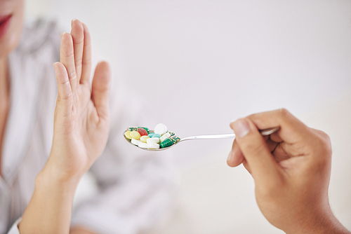 Crop shot of rejecting palm of woman unwilling to take spoon of pills