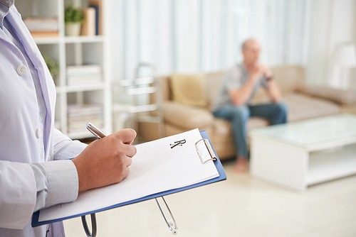 Doctor writing prescription for senior patient in his living room