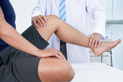 Doctor checking leg of patient with acute pain