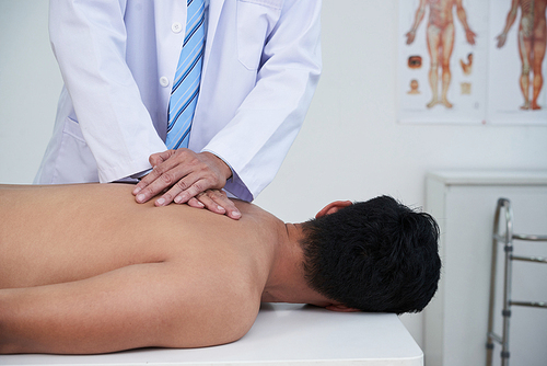 Cropped image of young man receiving back massage in clinic