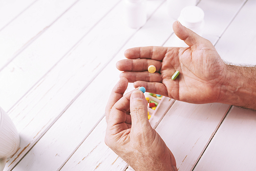 Hands of senior man taking pills and tablets