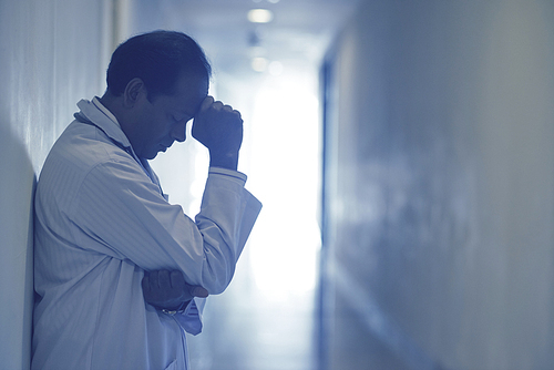 Side view of tensed male doctor standing in the hospital