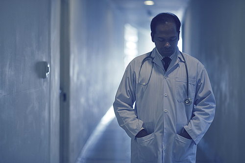 Stressed sad doctor walking along the corridor after losing a patient