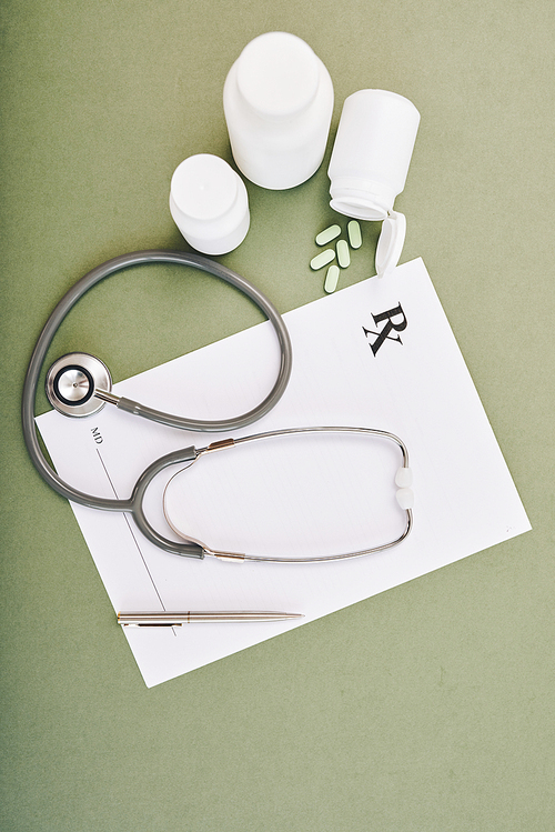 Stethoscope, blank prescription form and tablets on table