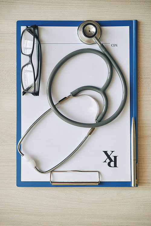 Stethoscope and glasses on empty prescription document