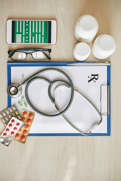 Medical insurance form, prescription document and tablets on desk of doctor