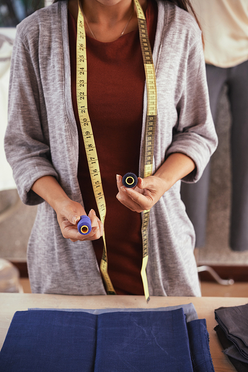 Cropped image of tailor choosing sewing thread color for blue fabric