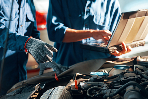 Hands of mechanics repairing car in auto service