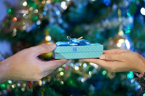 Hands of woman receiving Christmas present form her boyfriend