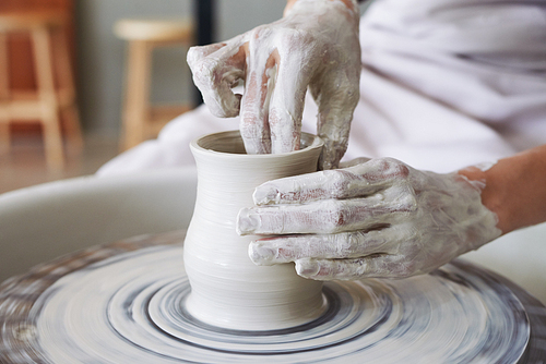 Hands of artisan enjoying making ceramic pot