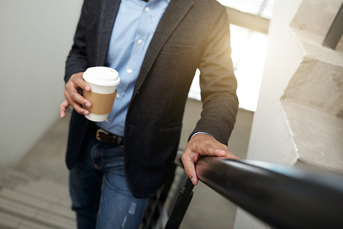 Cropped image of businessman with take-out coffee standing on stairs