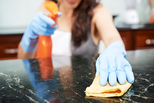 Close-up image of housewife wiping surface of kitchen table with detergent