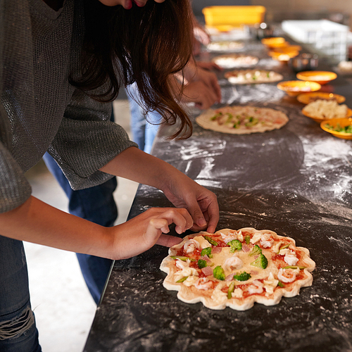 Cropped image of womak making pizza at cooking workshop