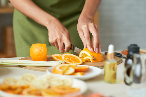 Close-up image of woman cutting orange to add it into soap she is making