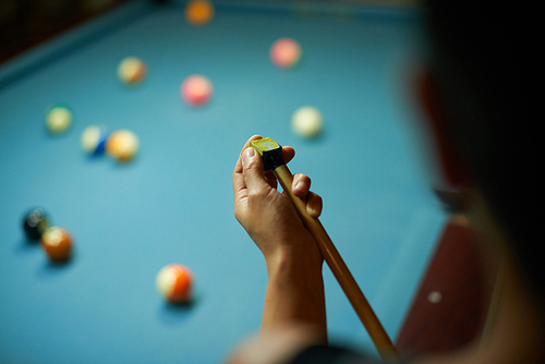 Hands of player chaking cue and waiting for her turn