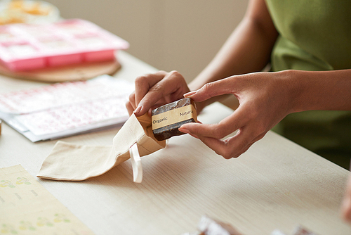 Woman purring organic soap bar she made into small sack