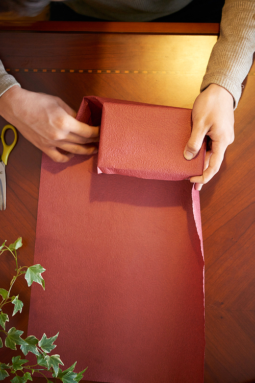 Hands of man using red wrapping paper for Christmas present decoration