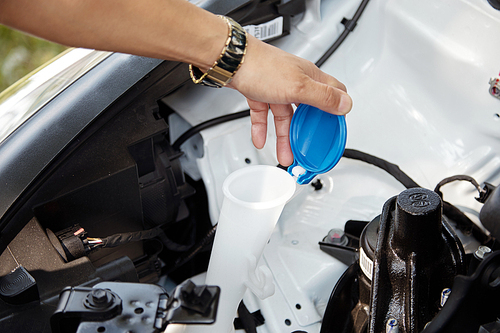 Car owner checking level of windshield washer fluid