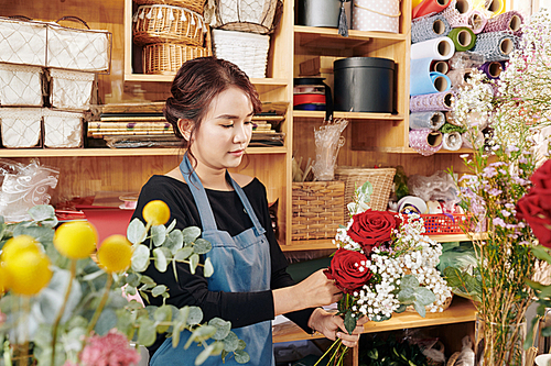 Young Asian florist making beautiful bouquet for customer