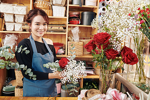 Portrait of pretty creative young florist working in her studio