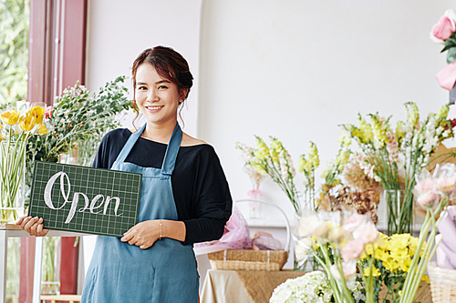 Small business concept. Pretty young Asian woman opening flower shop and welcoming clients