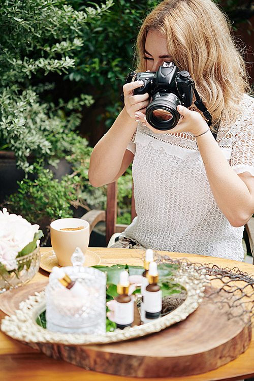 Professional photographer taking photos of organic cosmetics on silver tray outdoors