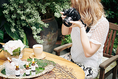 Woman using digital camera to take photos of organic cosmetics for social media and online store