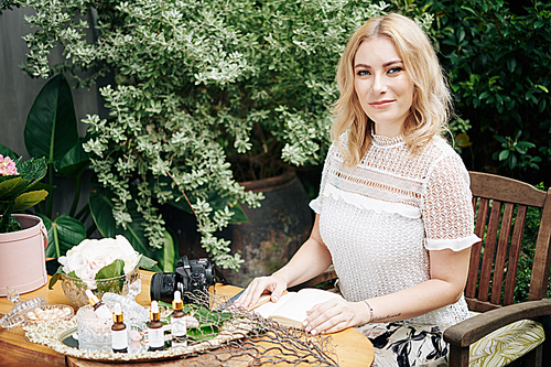 Portrait of pretty smiling woman working on business plan for development of her organic cosmetics brand