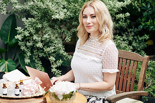 Portrait of charming smiling young businesswoman working on website for her cosmetic brand