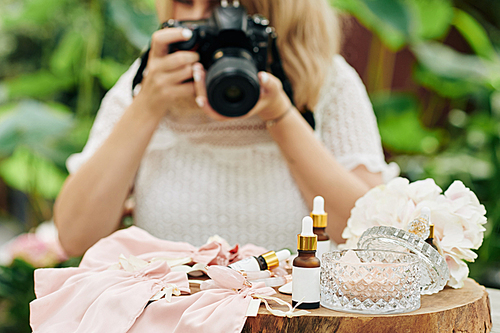 Woman taking photos of natural cosmetics like oils and essencials for advertising of cosmetics store