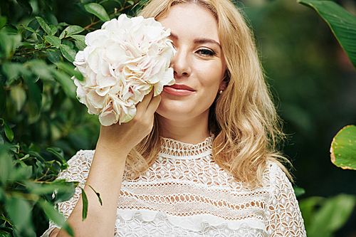 Portrait of young smiling beautiful woman with light pink blooming hydranea flower 