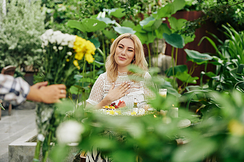 Pretty young woman happy to accept bouquet of beautiful flowers from her admirer