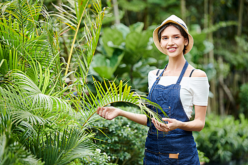 Portrait of pretty smiling young woman enjoying working in tropical garden