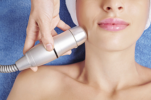 Close-up image of cosmetologist using professional machine for skin firming tratement in beauty salon