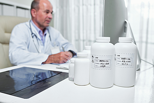 Various bottles with pills and tablets on table of general practitioner