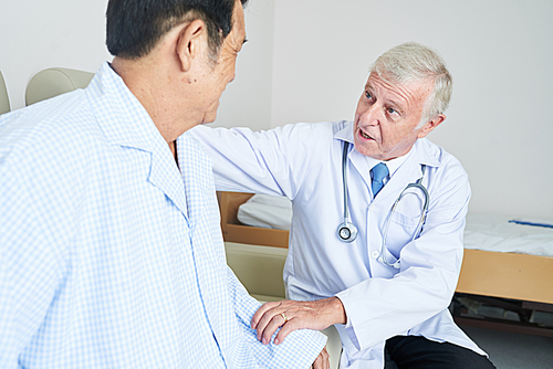 General practitioner talking to senior Vietnamese patient and convincing him to continue therapy