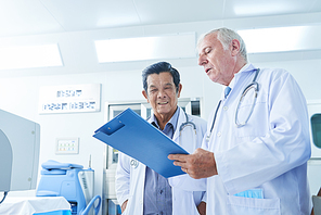 Doctor showing medical history of patient to his Vietnamese coworker and asking for advice