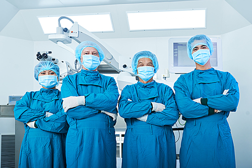 Positive confident proud surgeons in teal scrubs standing in operating room in front of medical equipment and 